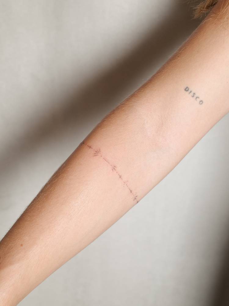 Ornamental bracelet tattoo done in fine line style, located on the forearm.