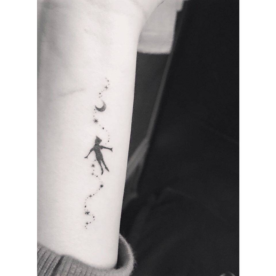 Peter Pan tattoo in cartoon style located on the wrist.