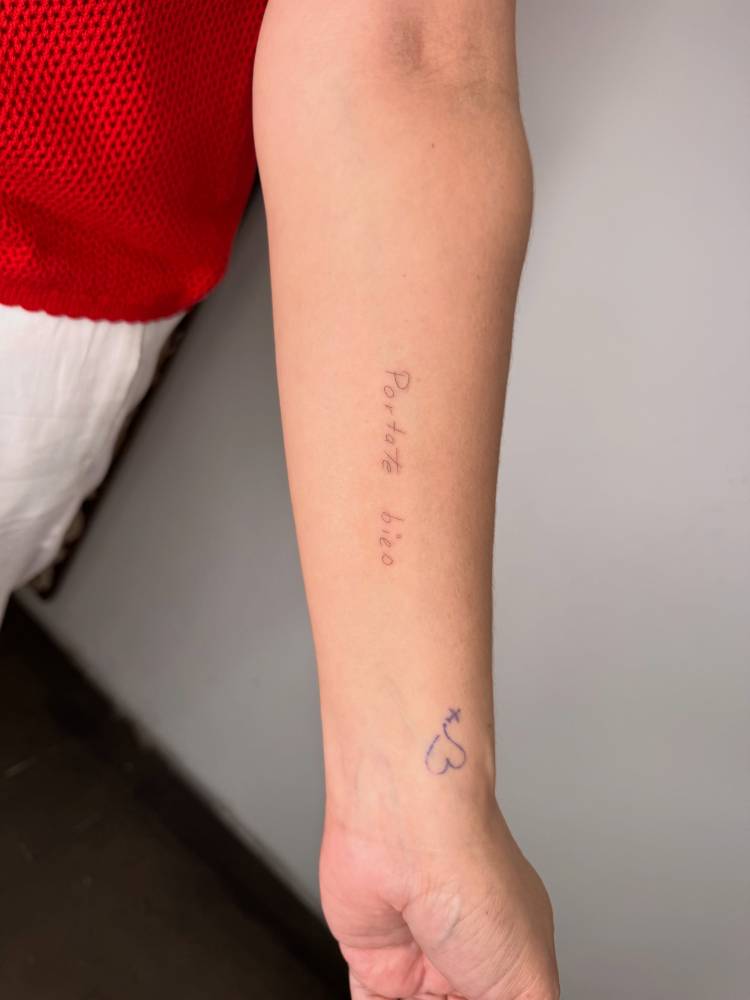 "Portate bien" lettering tattoo located on the inner forearm.