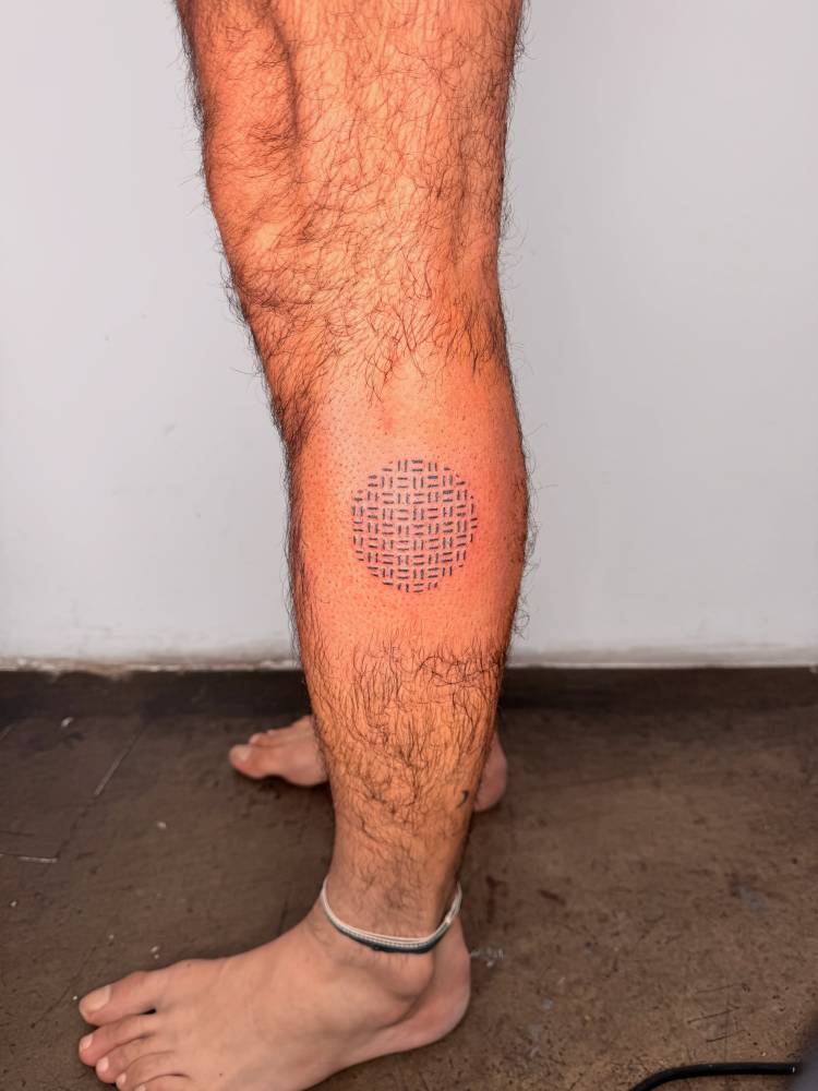 Geometric style pattern in the shape of a circle tattooed on the calf.