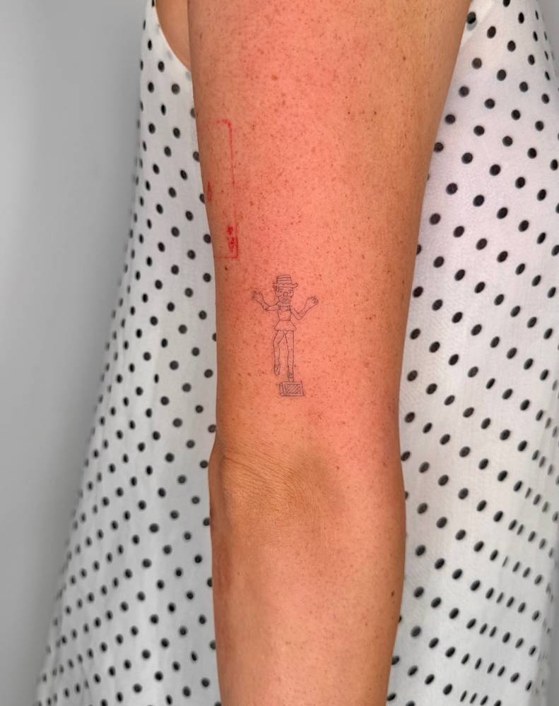 Fine line style ballerina tattoo located on the tricep.