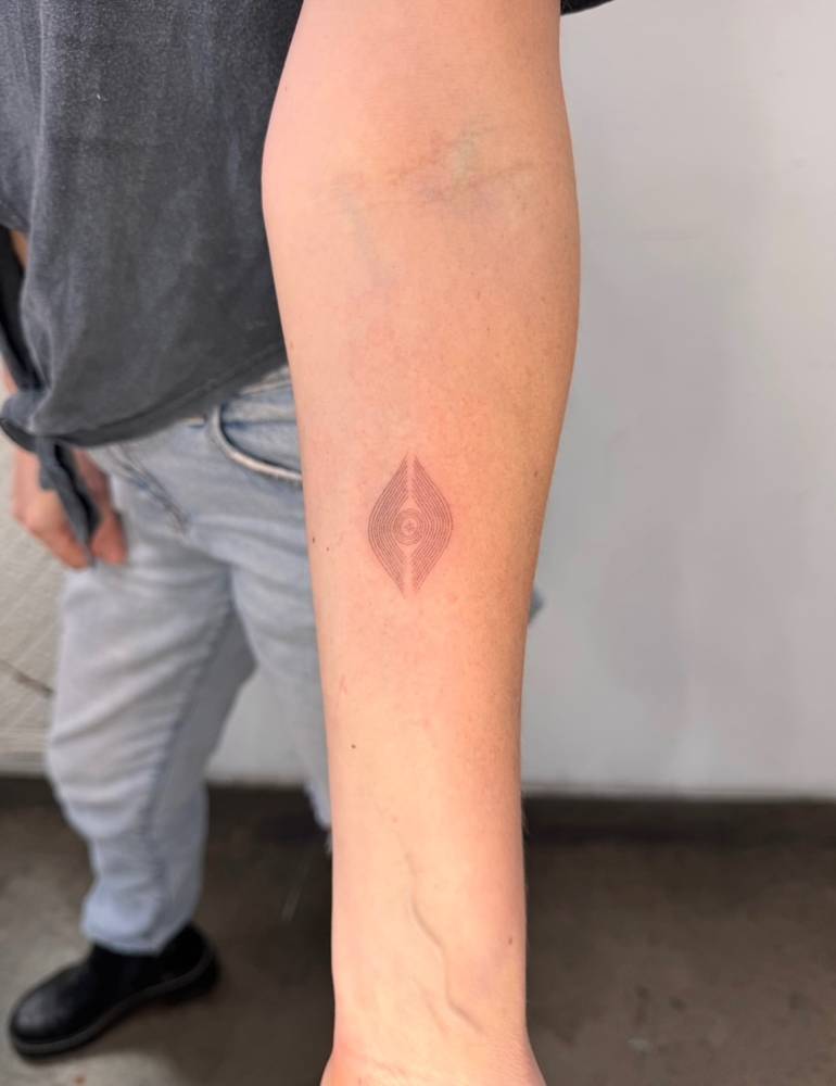 Single needle abstract geometric figure tattooed on the inner forearm.