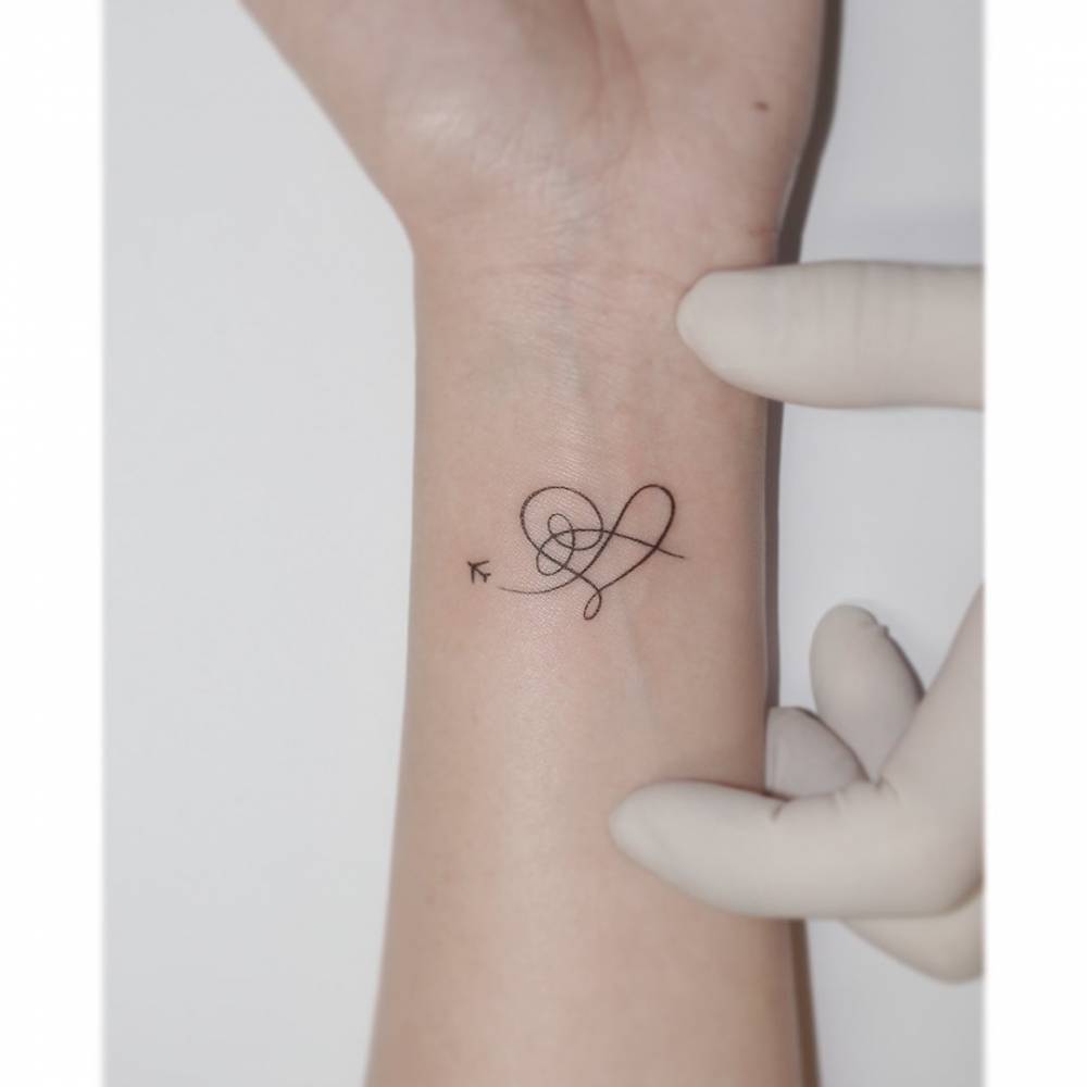 Airplane and heart tattoo located on the wrist.