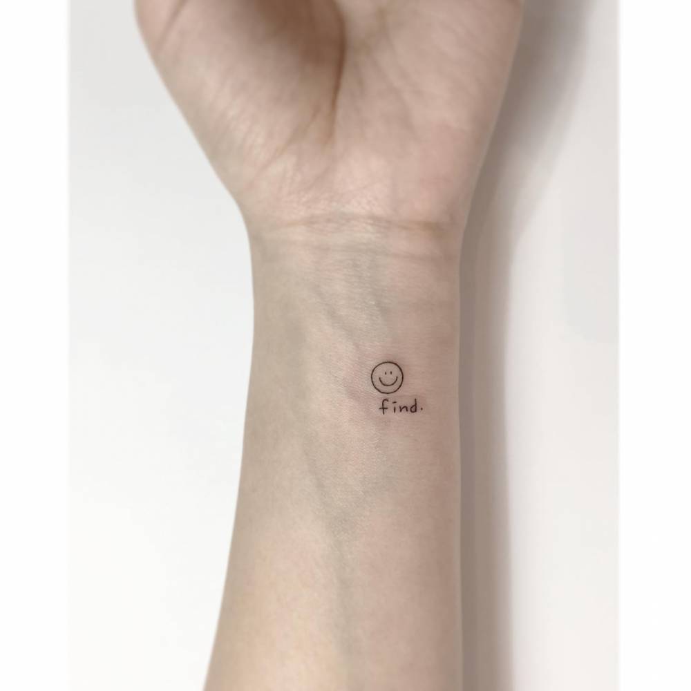 Smiley face and word "find" tattooed on the wrist.