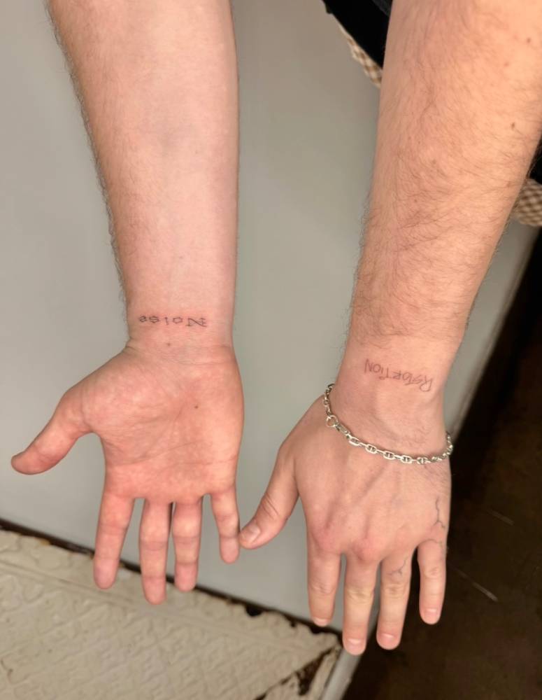 Words "noise" and "distortion" tattooed on the wrists.