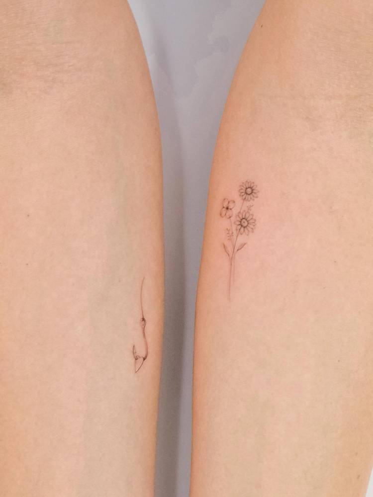 Fish hook and flower bouquet tattoos in fine line style.
