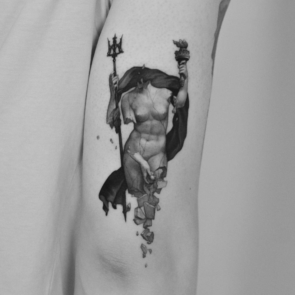 Broken Greek sculpture tattoo located on the tricep.