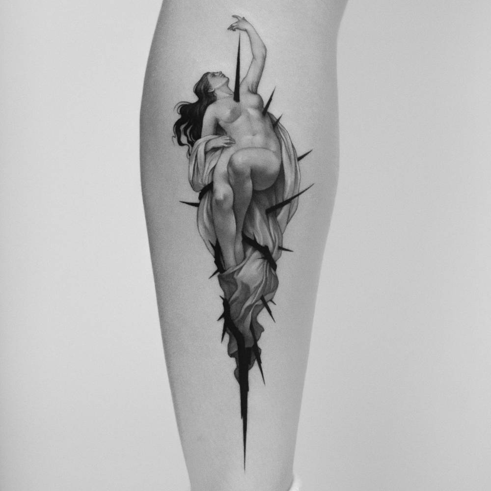 Nude woman and thorns tattoo in classical style located on the calf.