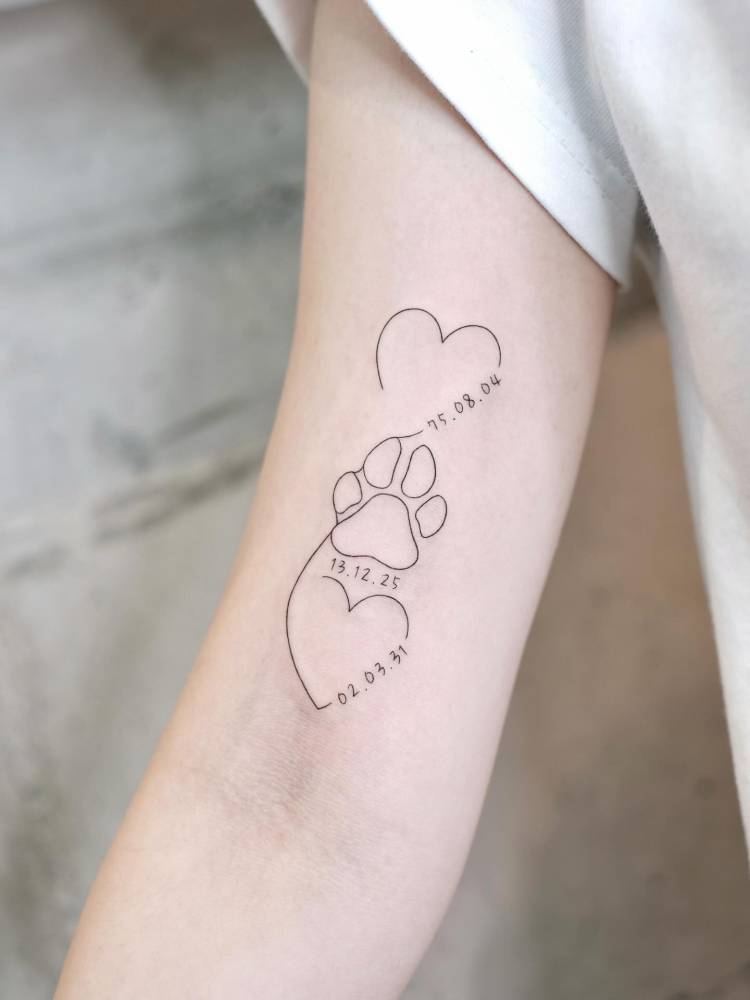 Hearts, dates and dog paw print tattoo located on the bicep.