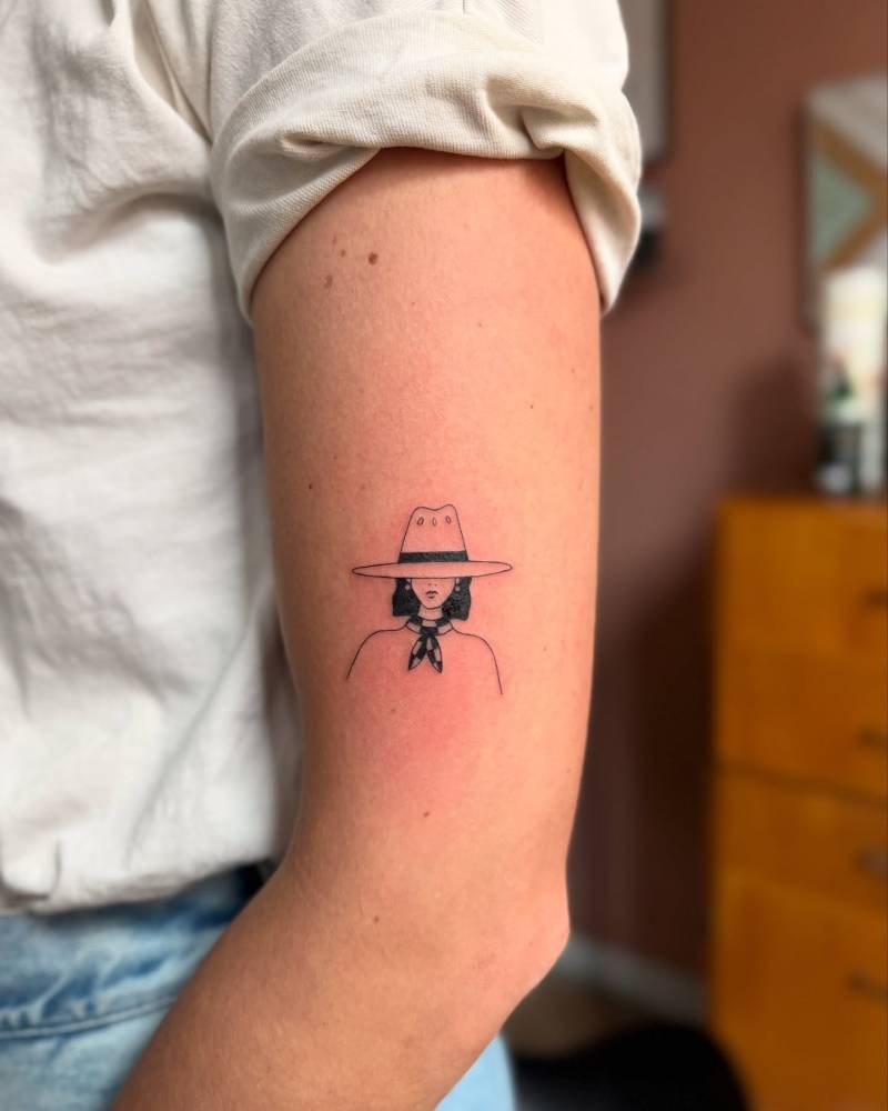 Cowgirl portrait tattoo in illustrative style located on the upper arm.