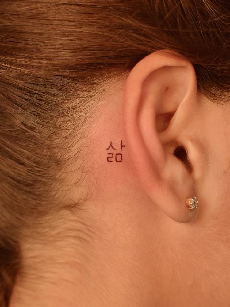 Korean word and number "20" tattooed behind the ear.