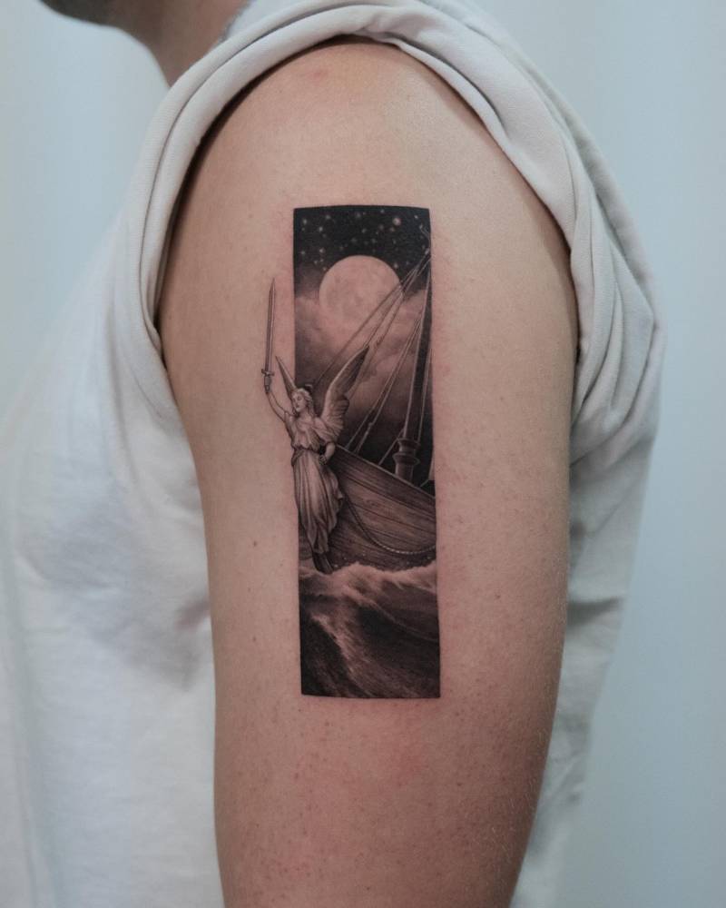 Angel and sailing ship tattoo located on the upper arm.