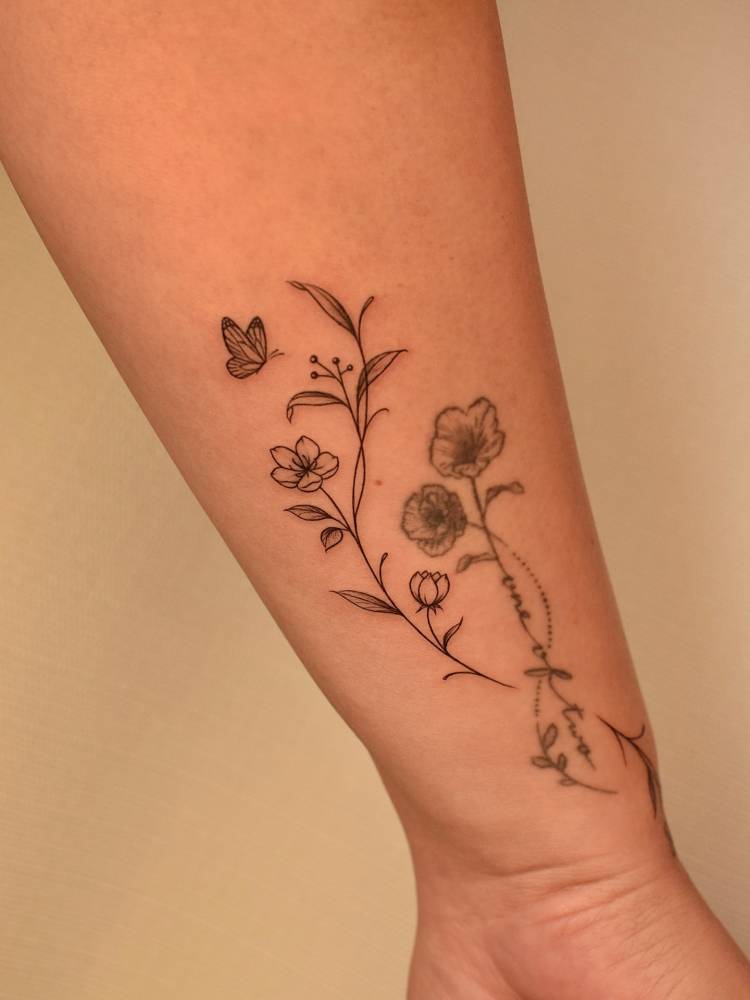 Butterfly and flowers tattoo located on the wrist, fine line style.