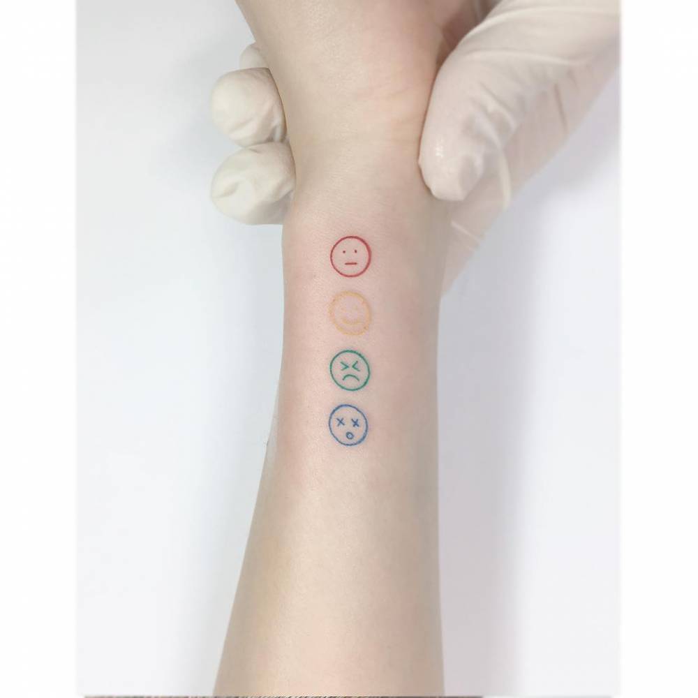 Face emojis tattooed on the wrist, minimalistic style.