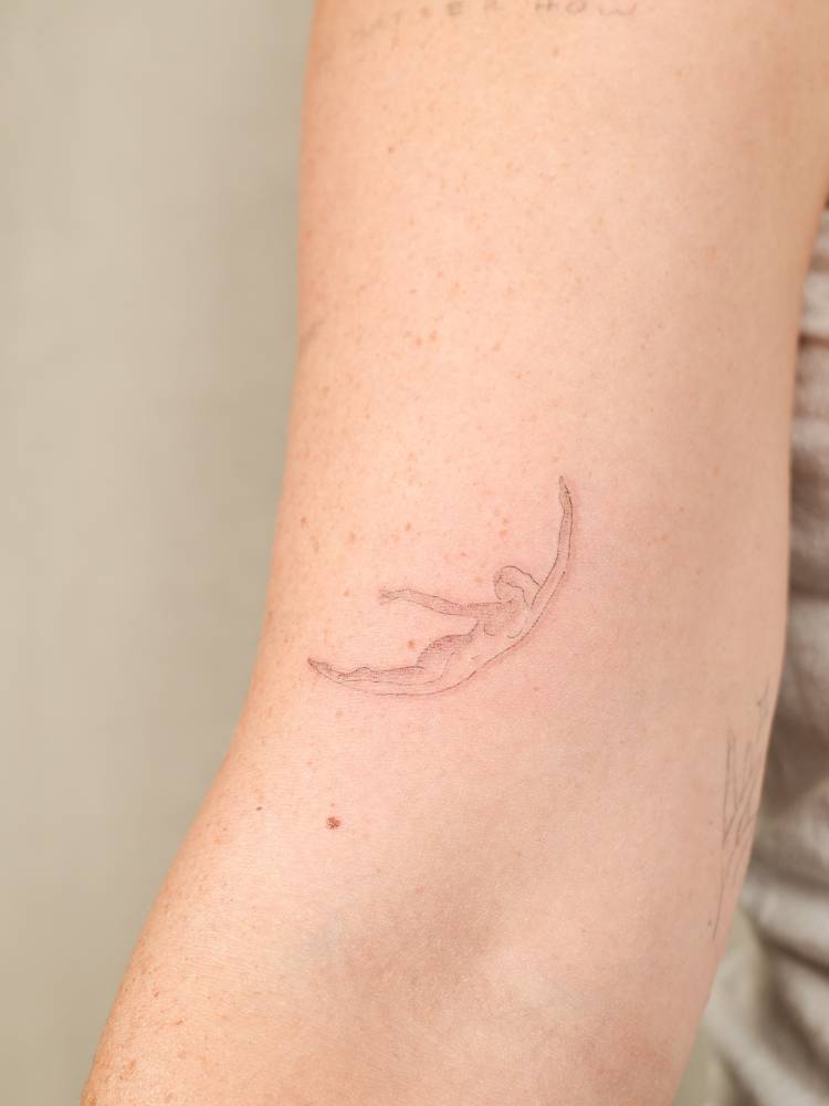 Crescent lady tattoo placed on the bicep, fine line style.