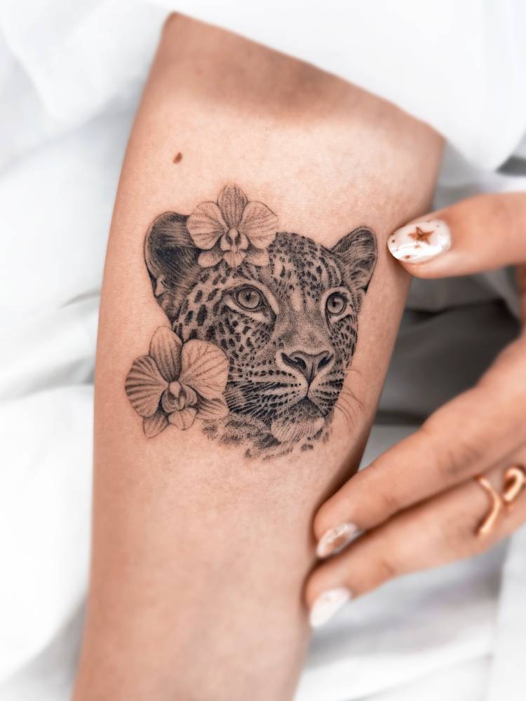 Leopard portrait and orchids tattoo located on the inner forearm.