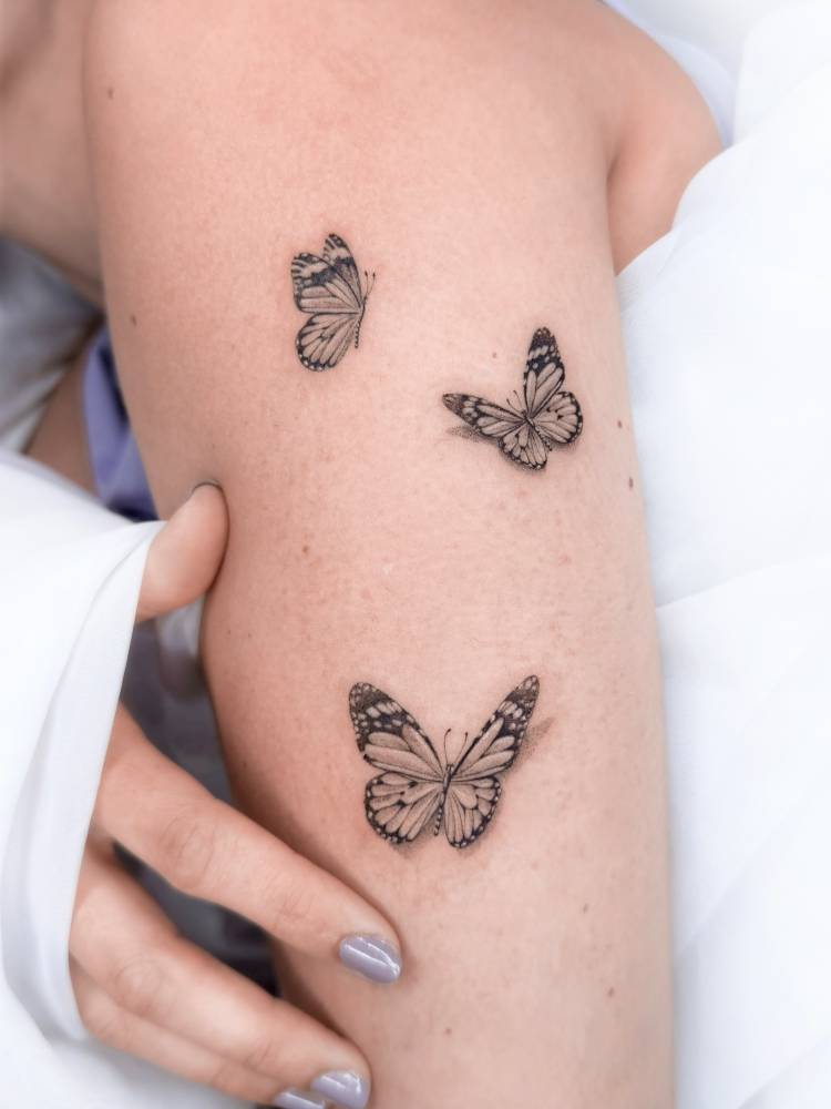 Micro-realistic style butterflies tattoo placed on the upper arm.