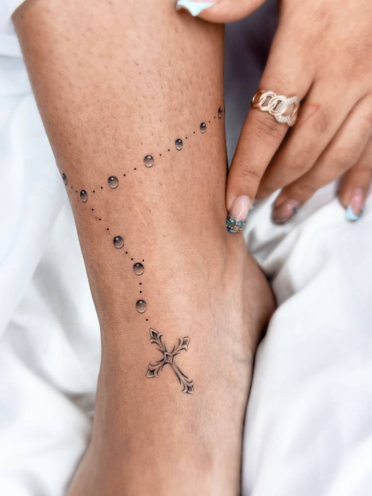 Rosary tattoo located on the ankle, done in illustrative style.