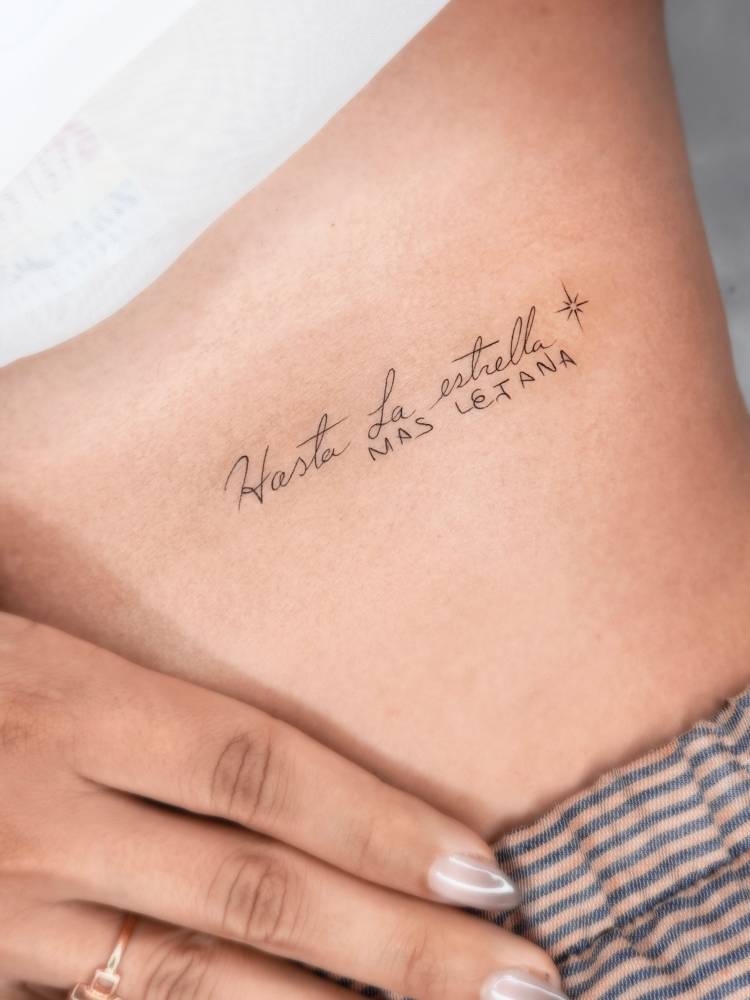 "Hasta la estrella mas lejana" lettering tattoo located on the rib.