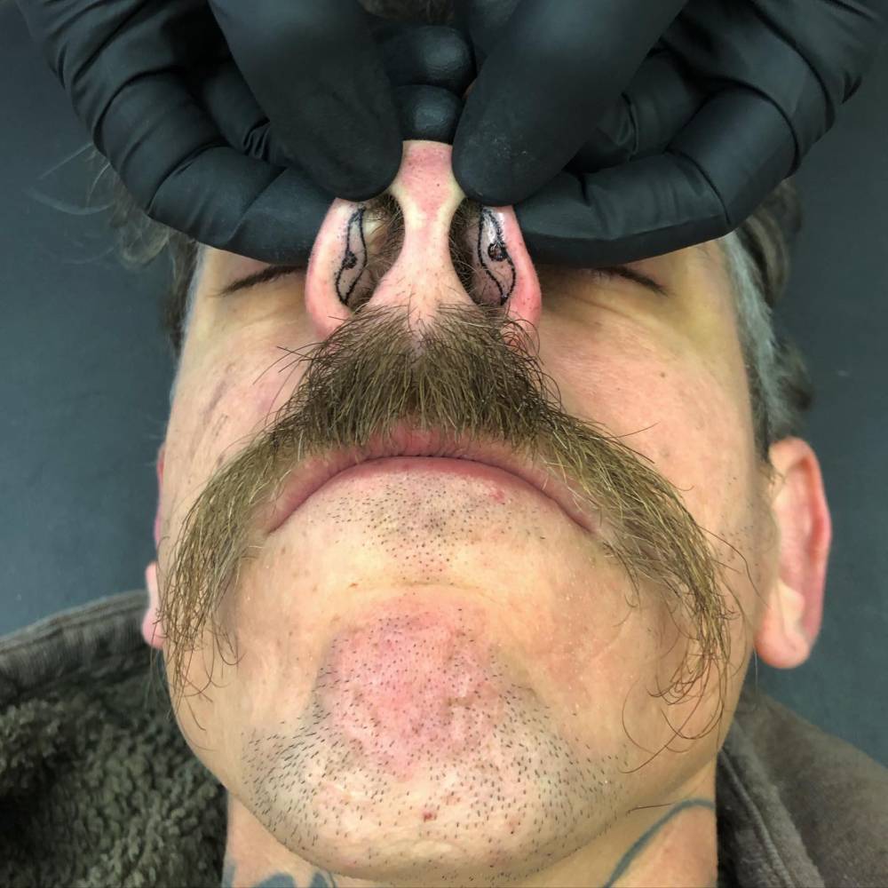 Hand poked tiny eyes tattoo located on the nostrils.