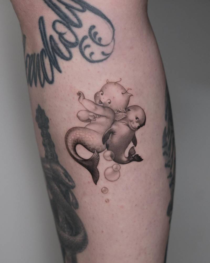 Kewpie mermaid and seal tattoo located on the calf.