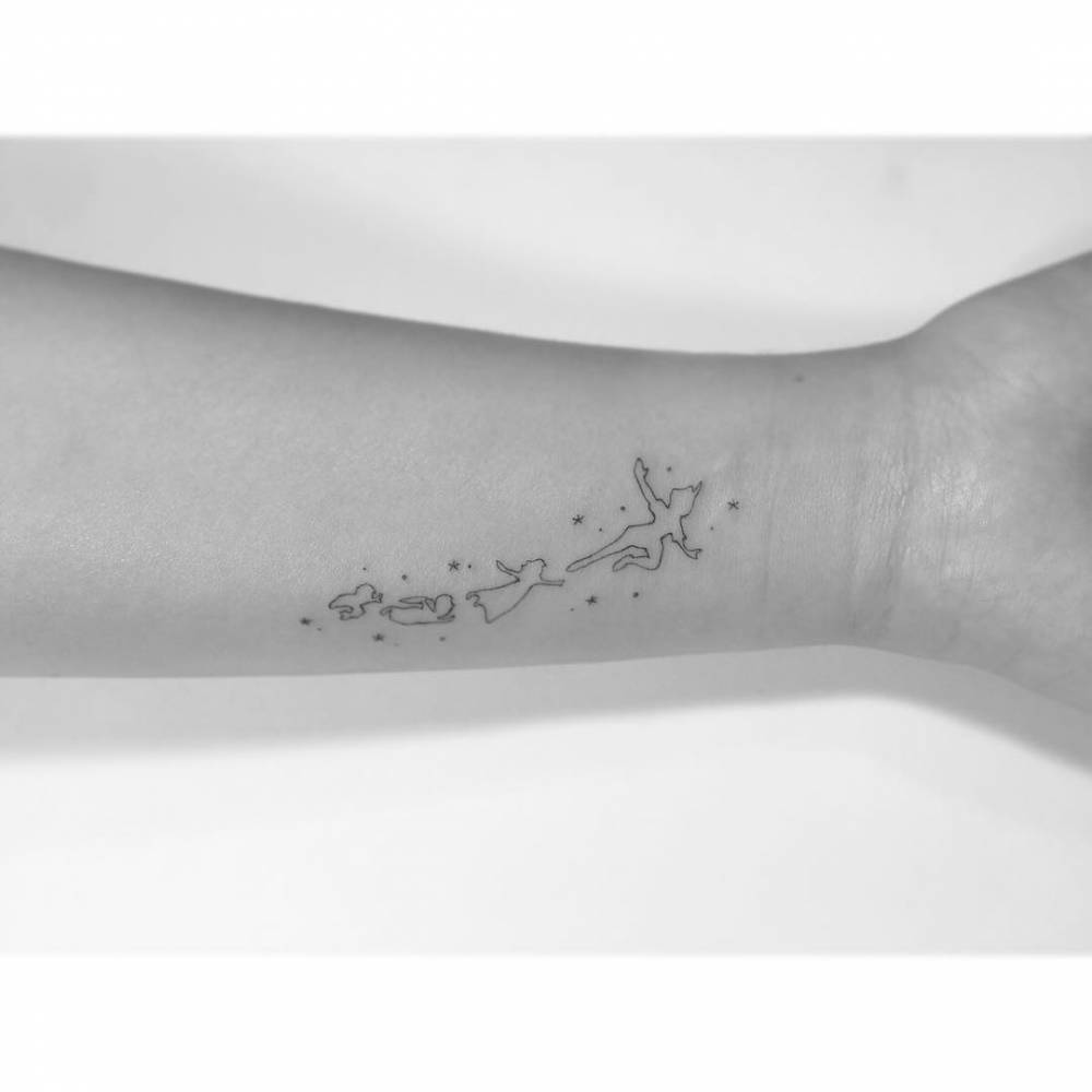 Peter Pan tattoo in minimalist style located on the wrist.