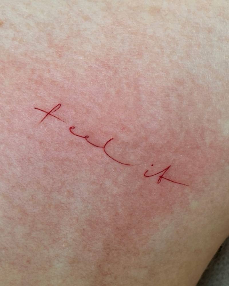 Handwritten font word "feel it" tattooed on the inner forearm.