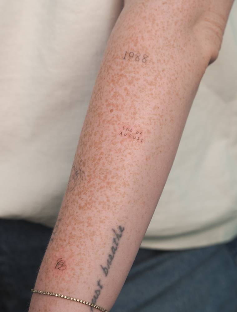 "End of August" lettering tattoo located on the forearm.