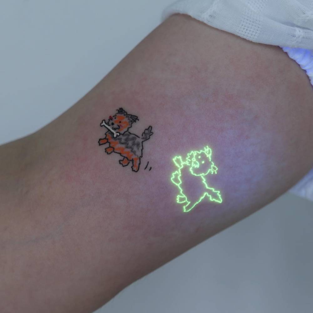 UV ink cartoon style dog tattoo located on the inner arm.