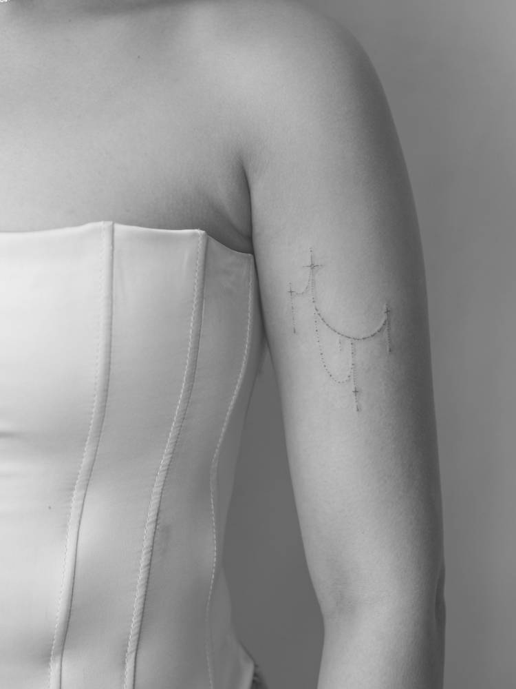 Fine line style ornamental tattoo placed on the upper arm.