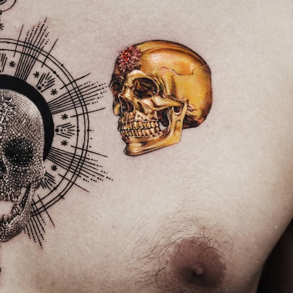 Micro-realistic style golden skull tattoo located on the chest.
