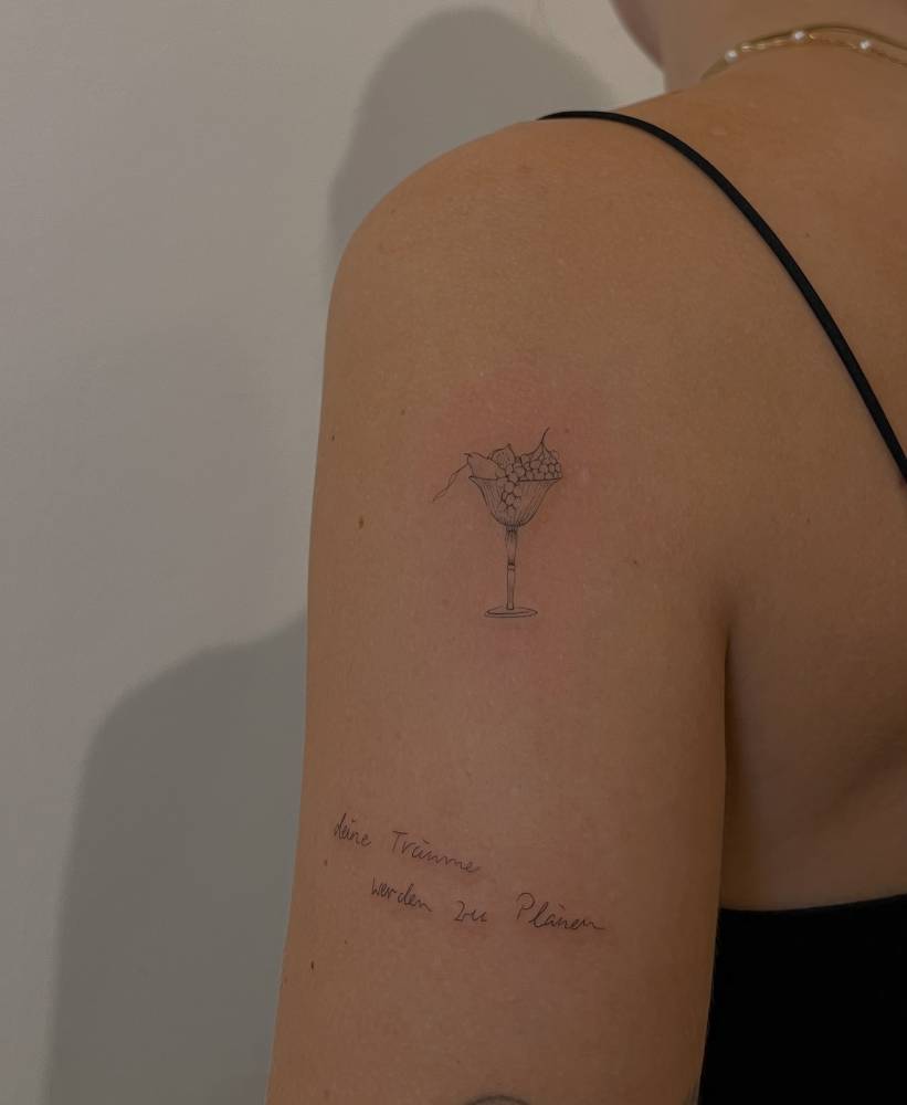 Fine line style fruit basket tattoo located on the upper arm.