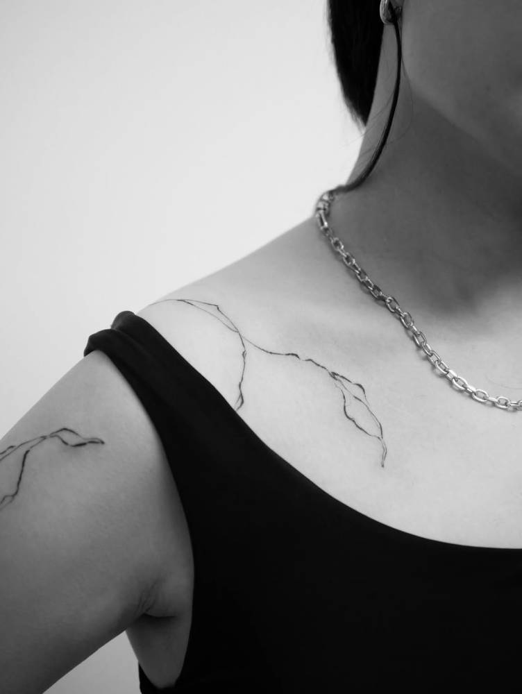 Illustrative style leaves tattoo located on the collarbone.