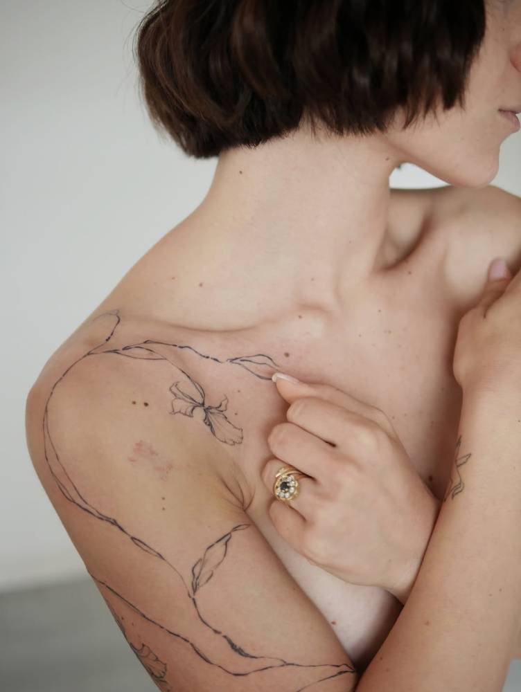 Flower design tattooed on the shoulder, illustrative style.