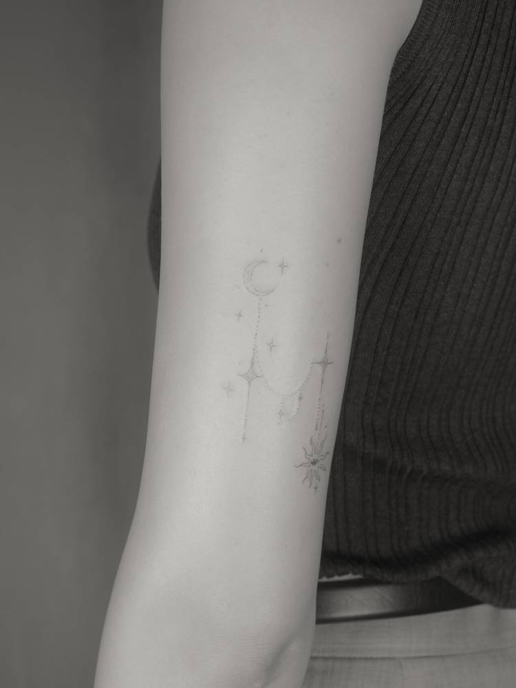 Ornamental moon and stars tattoo in fine line style.