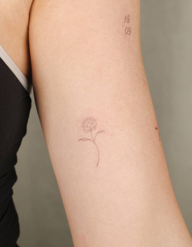 Fine line style flower tattoo located on the inner arm.
