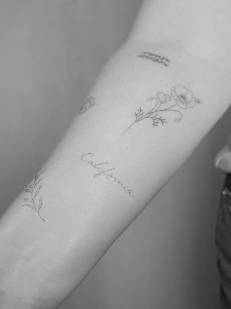 "California" lettering tattoo handwritten on the inner forearm.