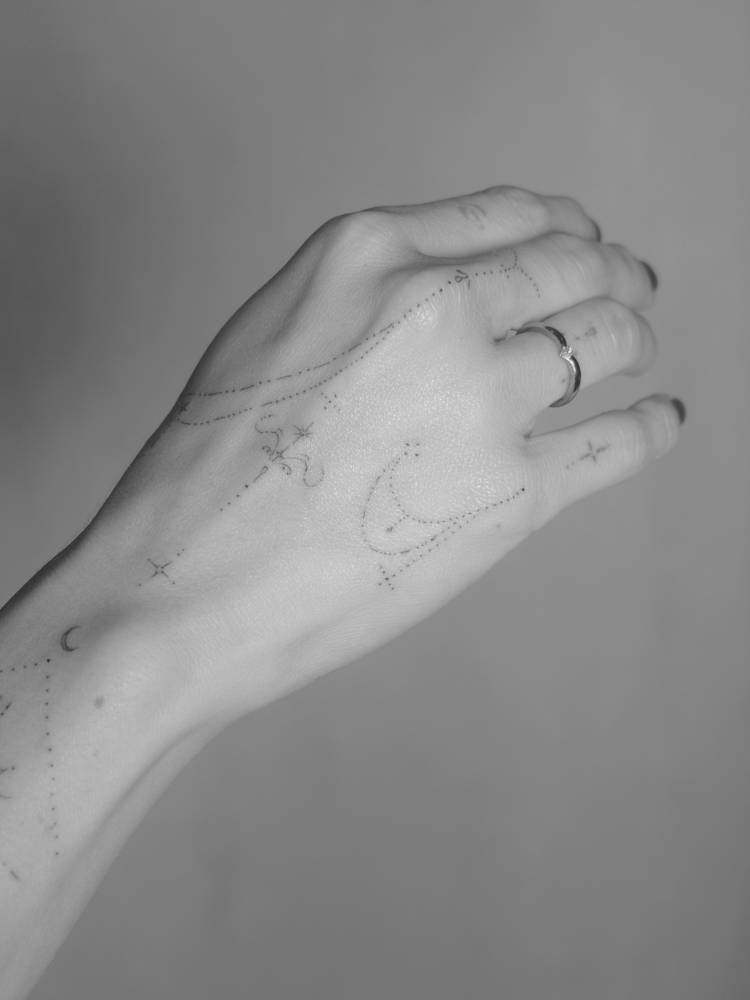 Ornamental design tattooed on the hand, done in fine line style.
