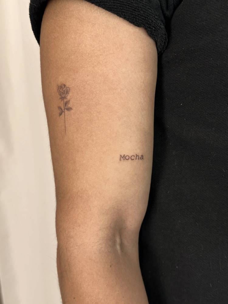 "Mocha" lettering tattoo in typewriter font located on the upper arm.