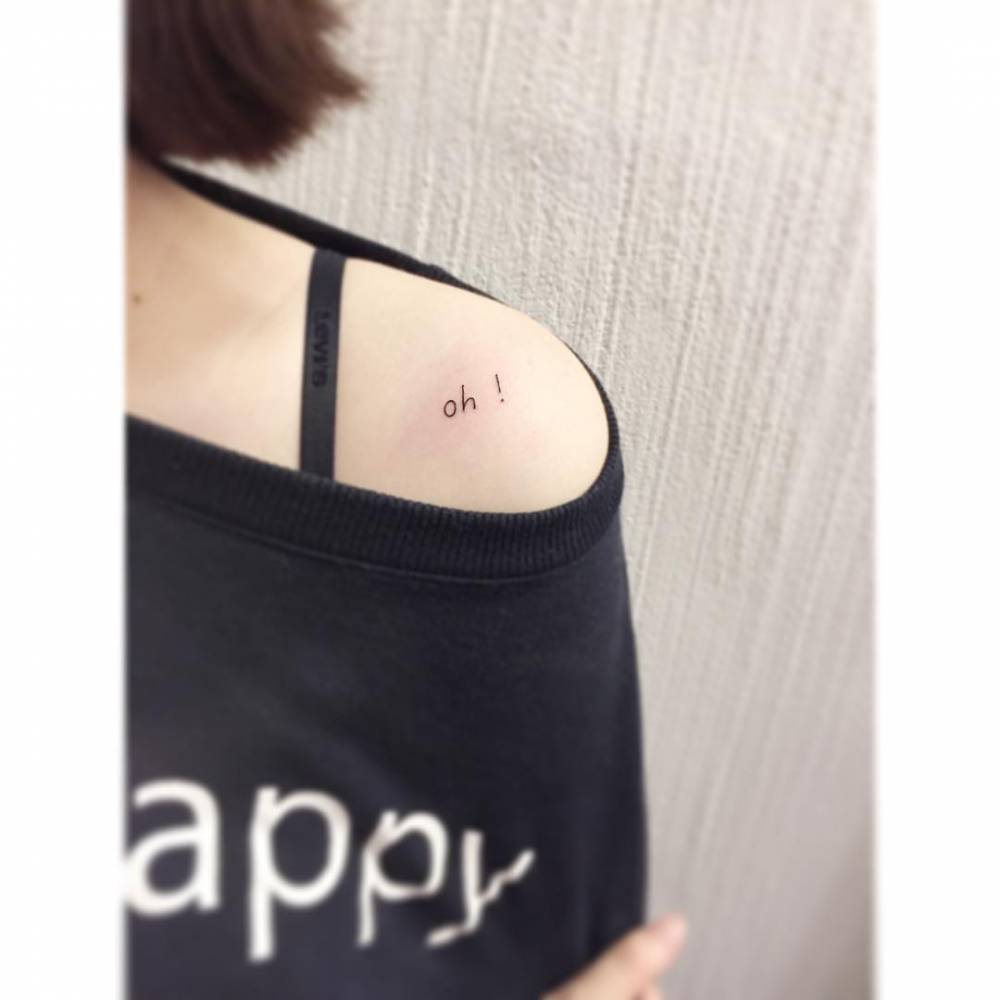 "Oh!" lettering tattoo located on the shoulder.