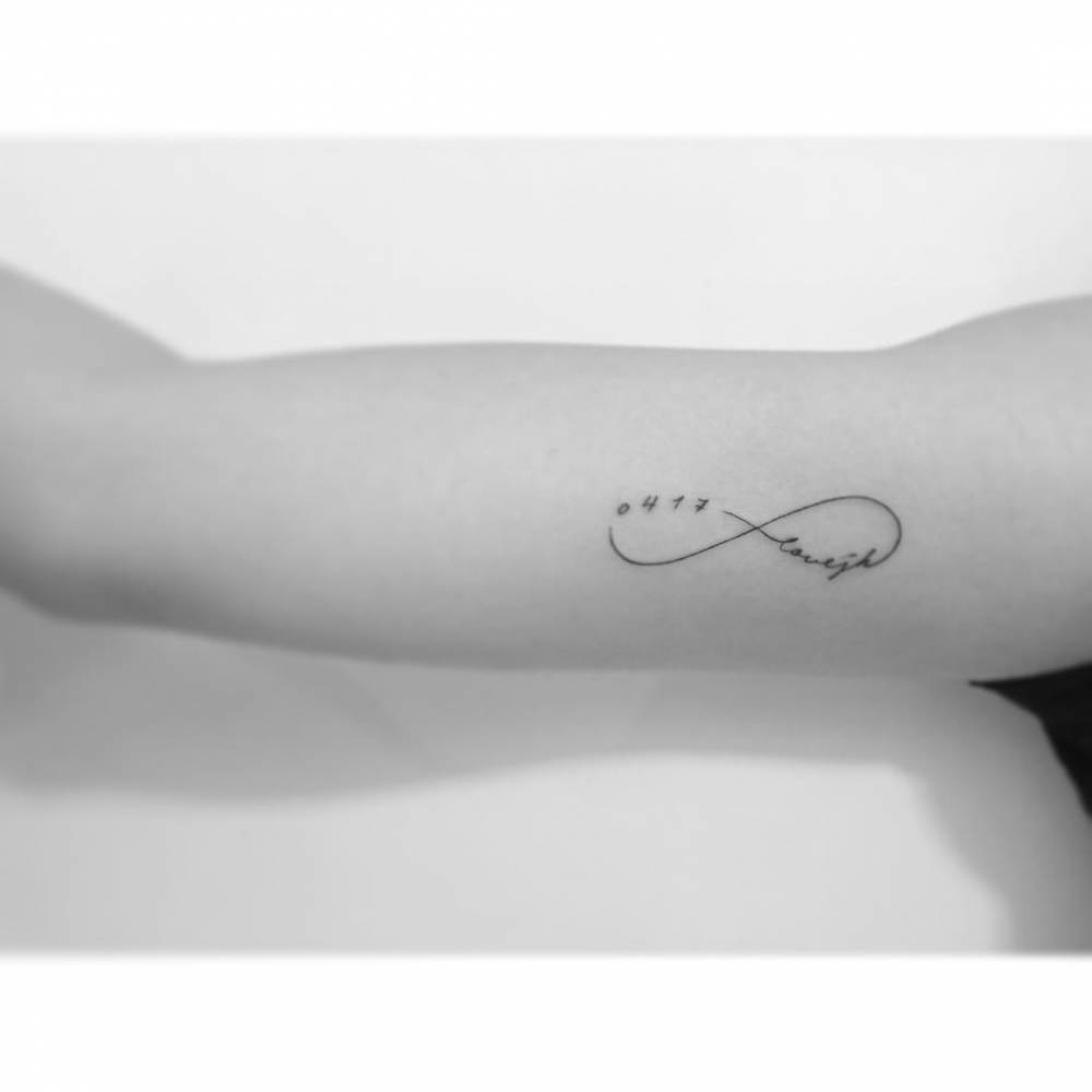Infinity symbol with date and name tattooed on the inner arm.