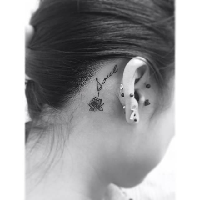 Word "soul" and lotus flower tattoo located behind the ear.