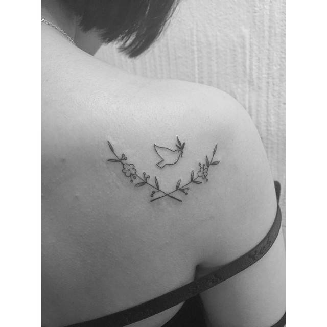 Flower wreath and dove of peace tattoo located on the shoulder.