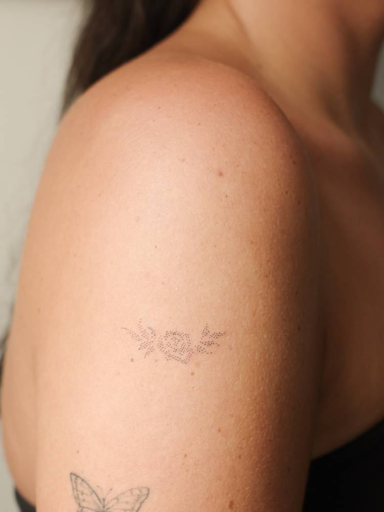 Dotwork style flower tattoo located on the upper arm.