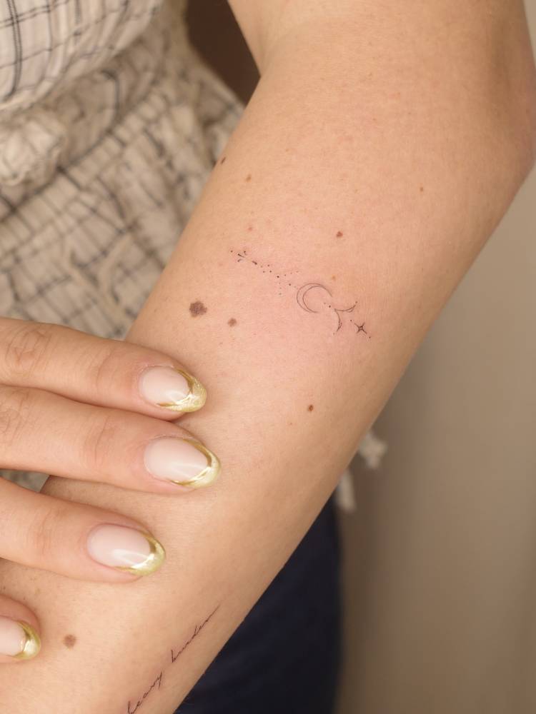 Fine line style ornamental moon tattoo located on the forearm.
