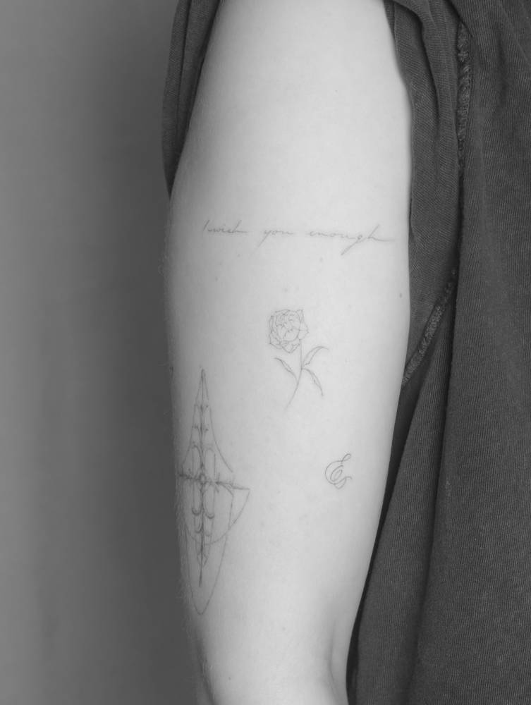 Peony flower tattoo in fine line style located on the upper arm.