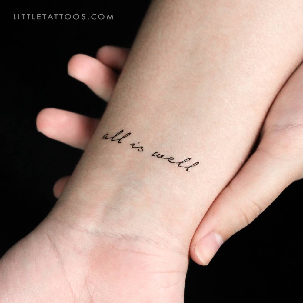 "All Is Well" temporary lettering tattoo in handwritten font.