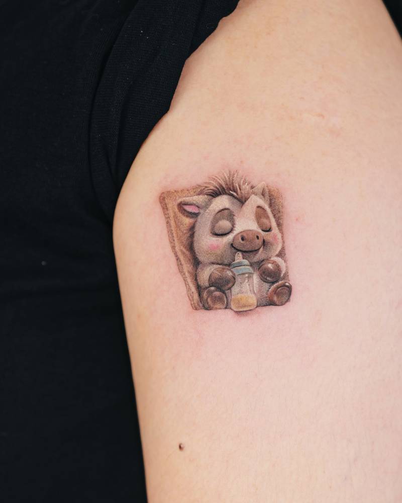 Cartoon style baby pig tattoo located on the upper arm.