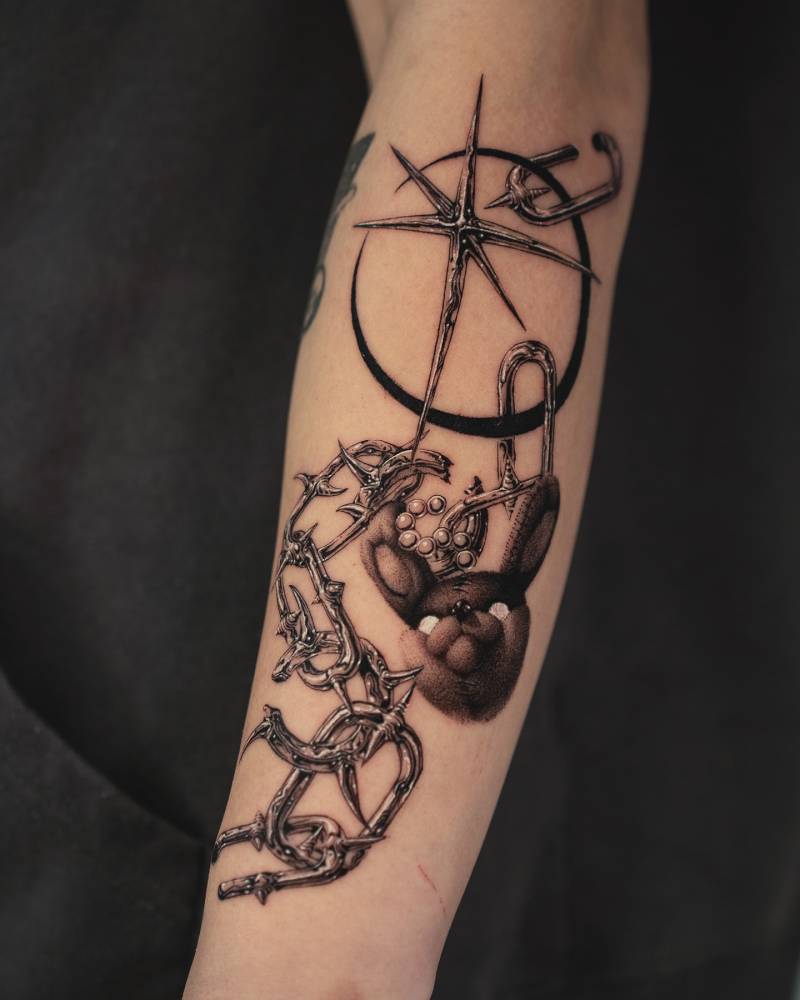 Black and grey broken chain and pendants tattoo located on the forearm.