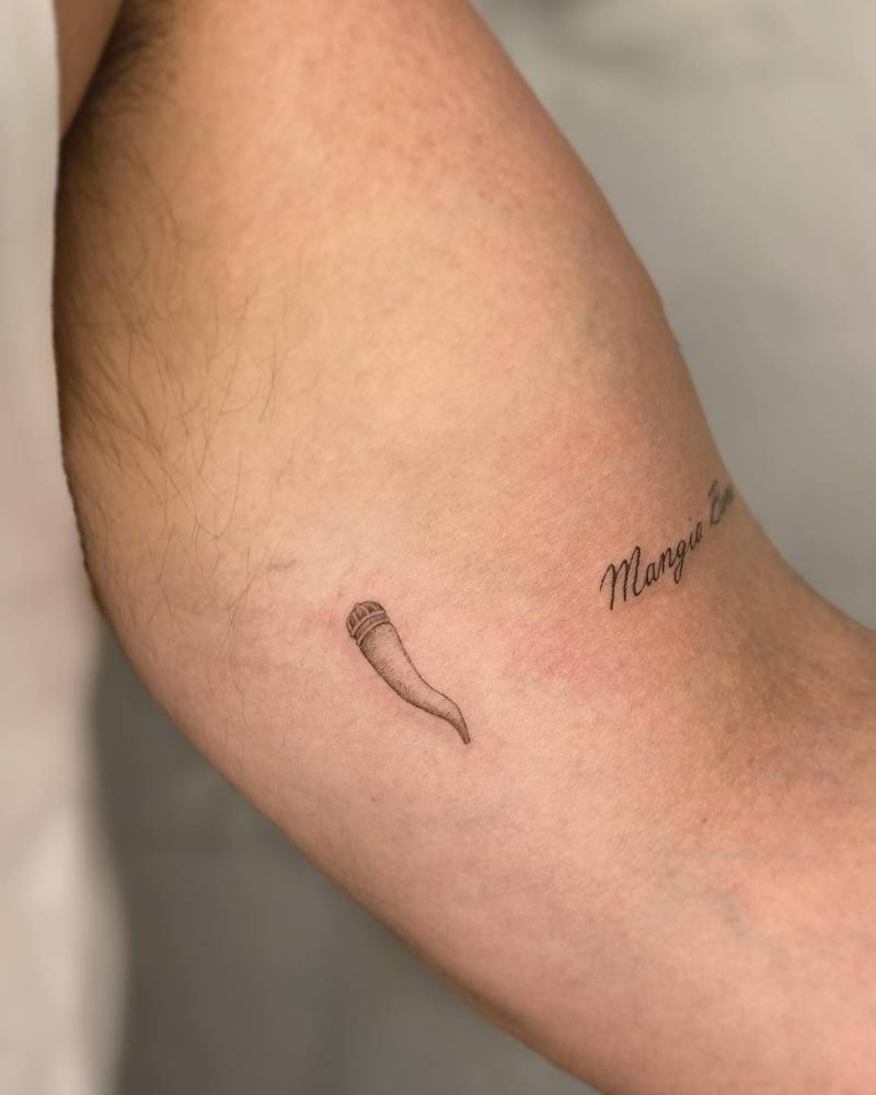 Illustrative style cornicello tattoo located on the inner arm.